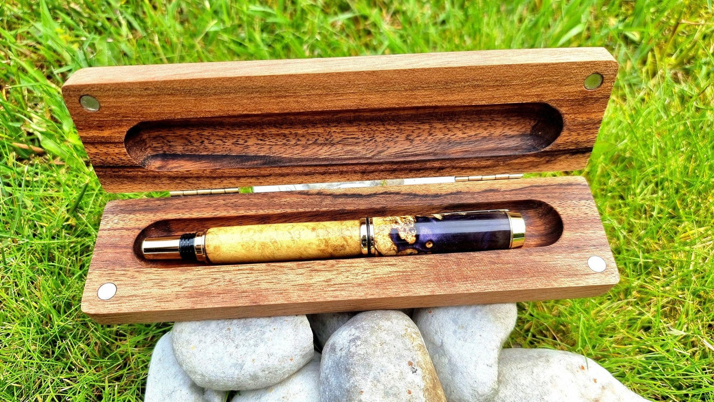 Handcrafted epoxy resin fountain pen placed on mossy stone outdoor setting