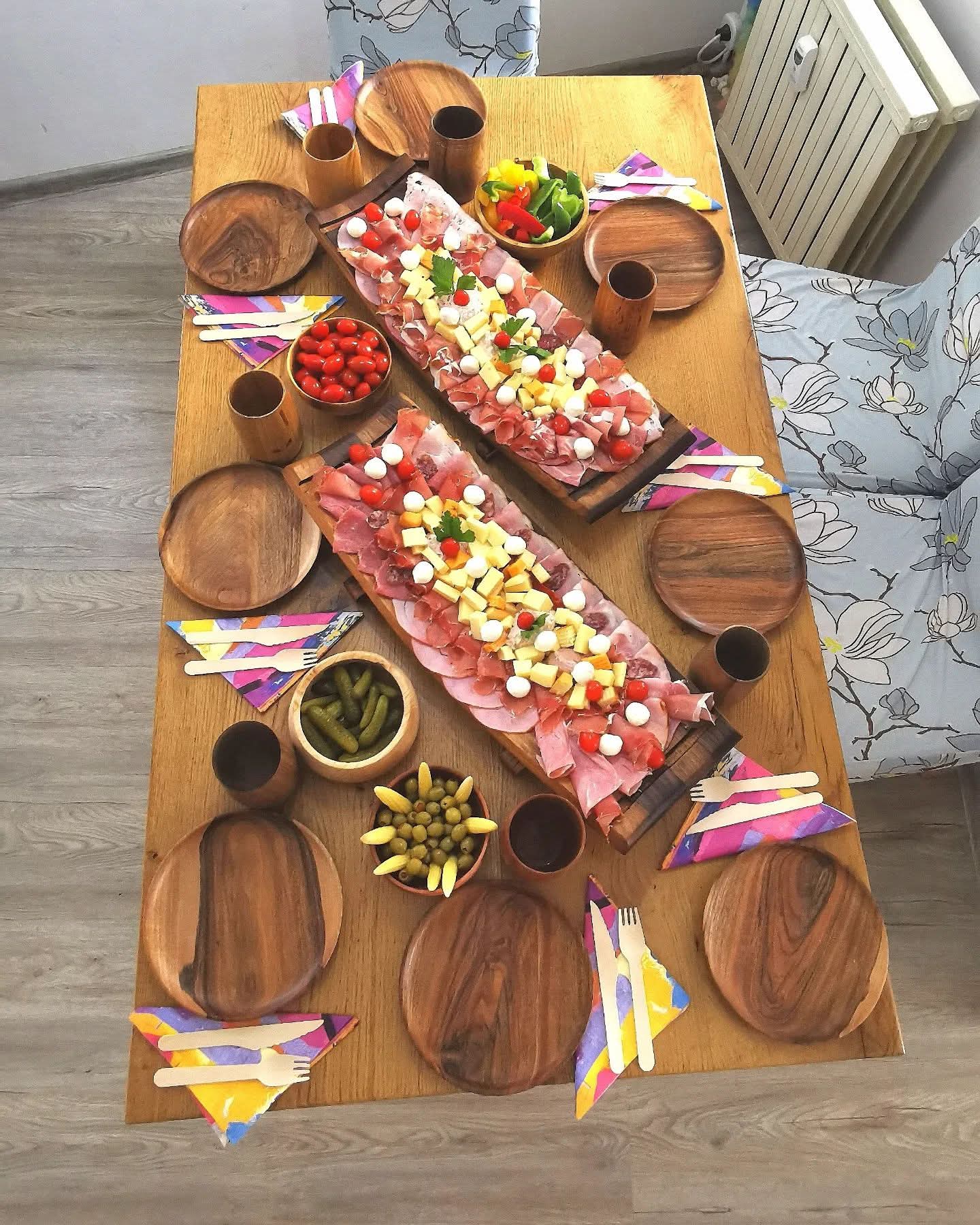 Wooden table set with various food items and cutlery on a wooden floor.