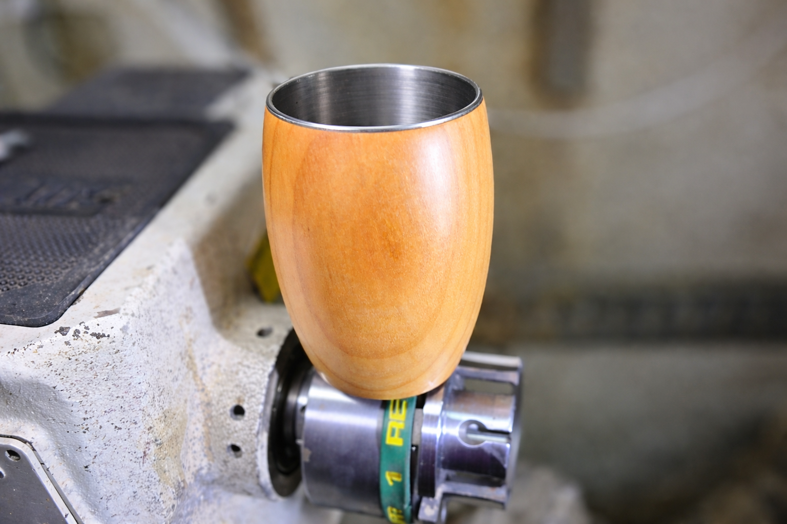 Handmade cherry wood cup on woodturning lathe showing artisan craftsmanship