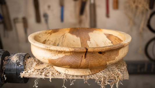 Handmade spalted beech wood bowl on woodworking lathe in workshop