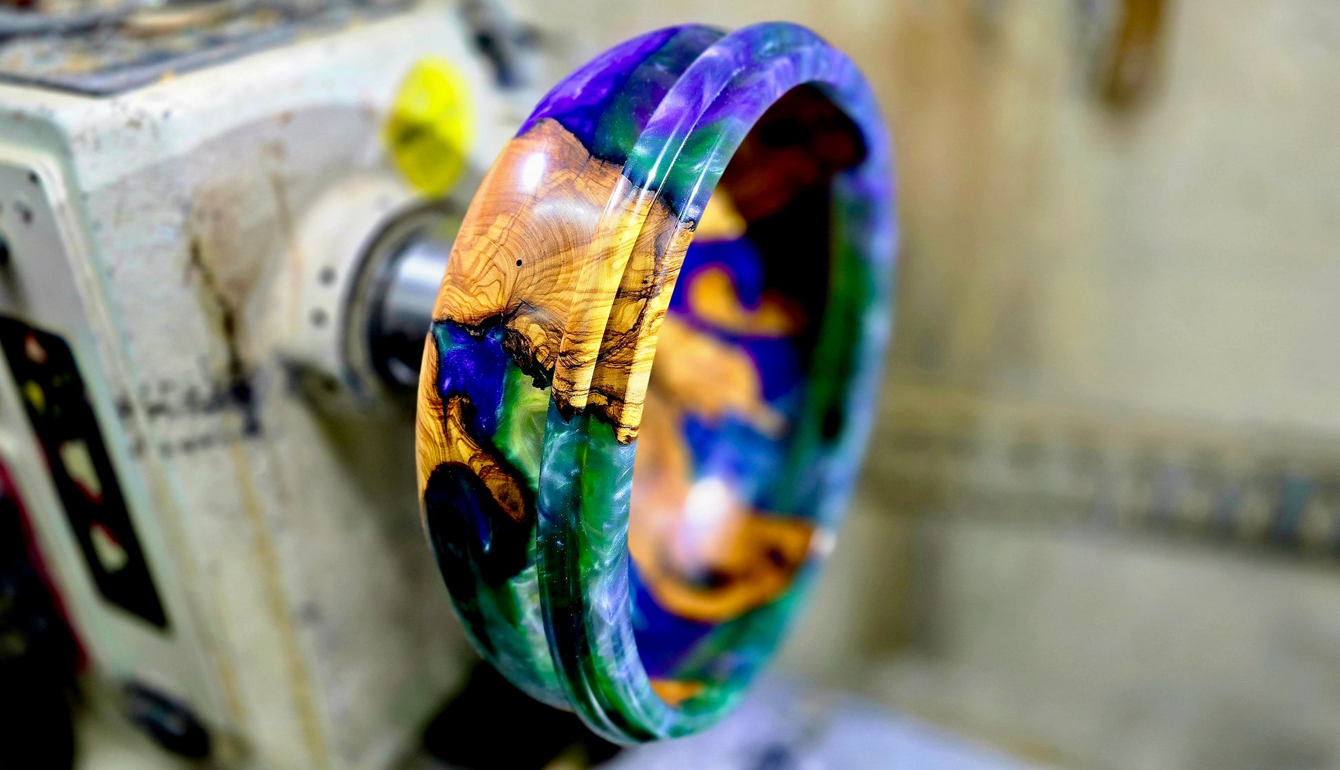 Handmade olive wood epoxy resin bowl being turned on the lathe during the woodturning process