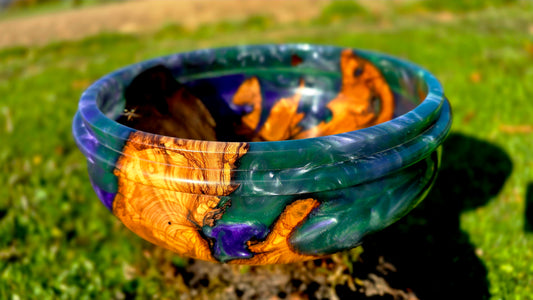 Handmade olive wood and epoxy resin bowl displayed outdoors in natural light, one of a kind artisan wooden art piece