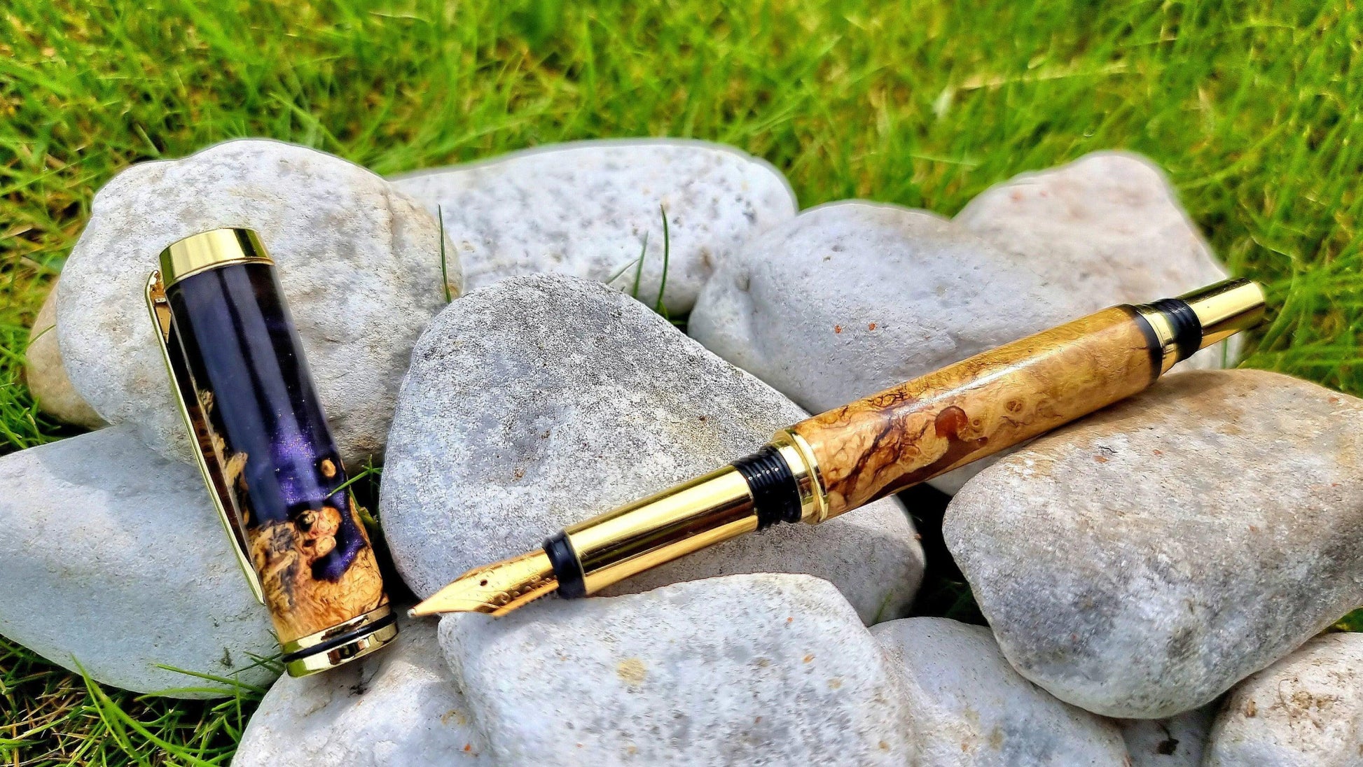 Handmade acacia burl and epoxy resin fountain pen displayed on natural stone background